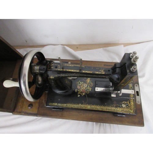 133 - A vintage wooden cased sewing machine with floral design.