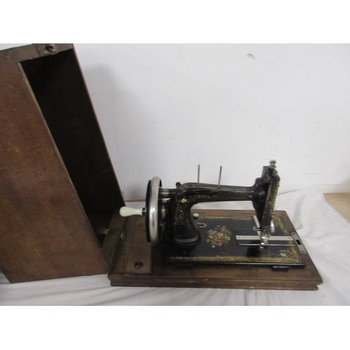 133 - A vintage wooden cased sewing machine with floral design.