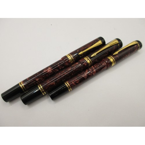26 - Three Parker Duofold Centennial pens with marbled maroon cap and barrels.  (1) Fountain pen with nib... 