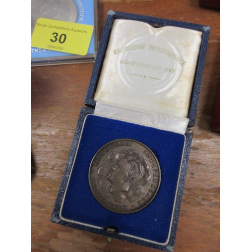 30 - A bronze Rhodesian Independence Medal, together with other cased commemorative medals and crowns, in... 