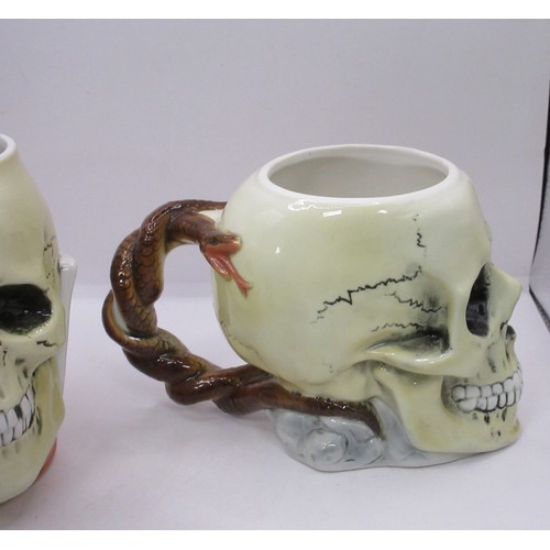 120 - Two German pottery skull tankards or beer steins. One with a serpent handle, the other with a top ha... 