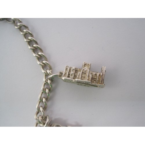 38 - A white metal charm bracelet, clasp stamped sterling, with eight white metal charms - York Minster, ... 