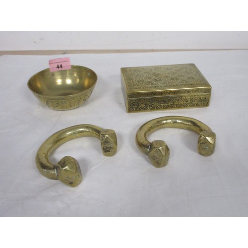 44 - Two heavy brass manillas, an engraved brass cigarette box marked Kinco, and a small brass bowl (diam... 