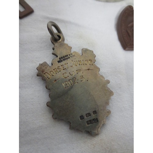 7 - A velvet box with white metal top containing an assortment of medals and fobs, including a sterling ... 