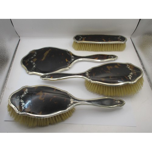 13 - An inlaid silver and tortoiseshell four-piece dressing table set comprising a clothes brush, two han... 