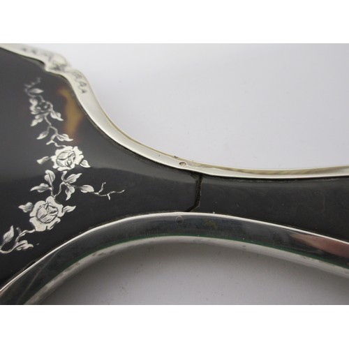 13 - An inlaid silver and tortoiseshell four-piece dressing table set comprising a clothes brush, two han... 