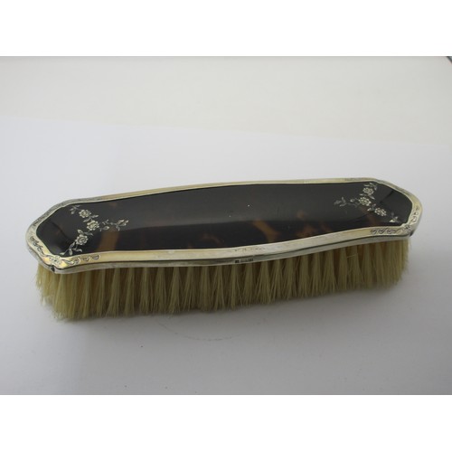13 - An inlaid silver and tortoiseshell four-piece dressing table set comprising a clothes brush, two han... 