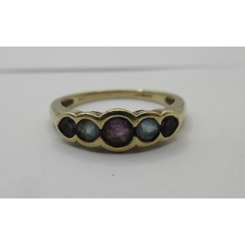 17 - A 9 carat imported gold ring set with a row of five stones (three amethysts spaced with two pale blu... 