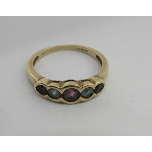 17 - A 9 carat imported gold ring set with a row of five stones (three amethysts spaced with two pale blu... 