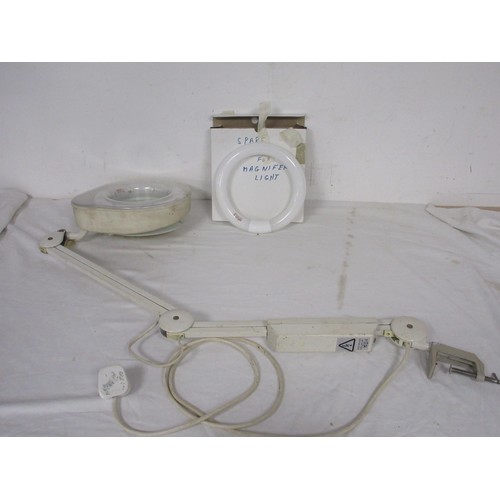 26 - A desk mounted lit and magnifying anglepoise lamp with spare ring bulb