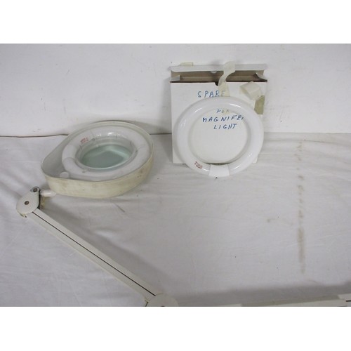 26 - A desk mounted lit and magnifying anglepoise lamp with spare ring bulb