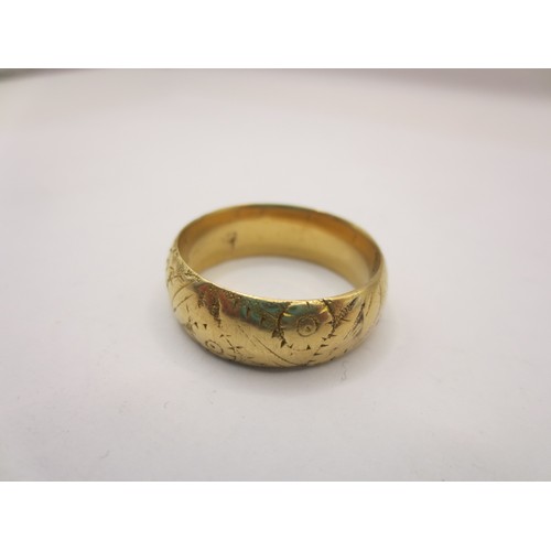 12 - A gold ring with partially worn foliate engraving,  size W/X, approx. 4.6g.  Acid test positive for ... 