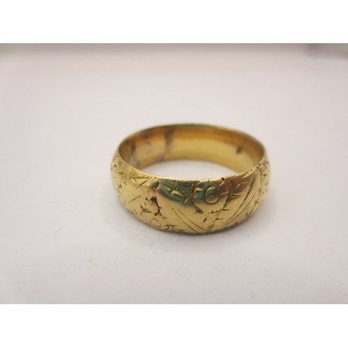 12 - A gold ring with partially worn foliate engraving,  size W/X, approx. 4.6g.  Acid test positive for ... 