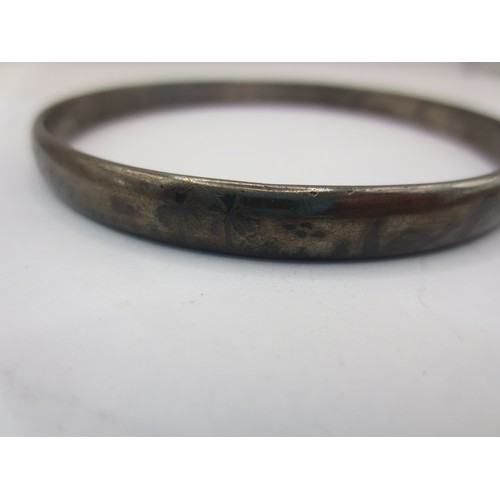 14 - A large white metal bangle engraved with palm trees, camels and sheep.  Acid tests positive for silv... 