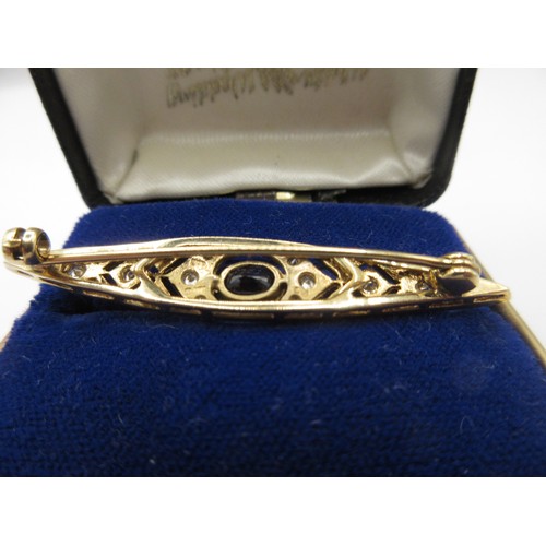 1 - A 9 carat gold brooch set with a central sapphire and twenty-two graduated brilliant cut diamonds.  ... 
