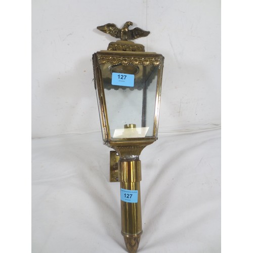 127 - A wall-mounting coaching style brass lamp, electric fitting, scallop shell border and surmounted by ... 