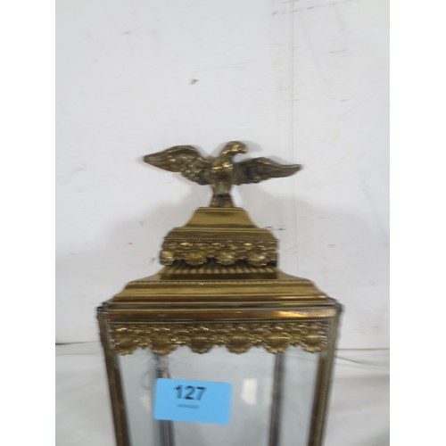 127 - A wall-mounting coaching style brass lamp, electric fitting, scallop shell border and surmounted by ... 