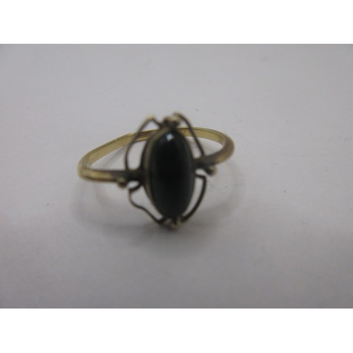 83 - An Edwardian yellow metal ring set with an oval striated green stone or bead (9mm x 4mm).  Gross app... 