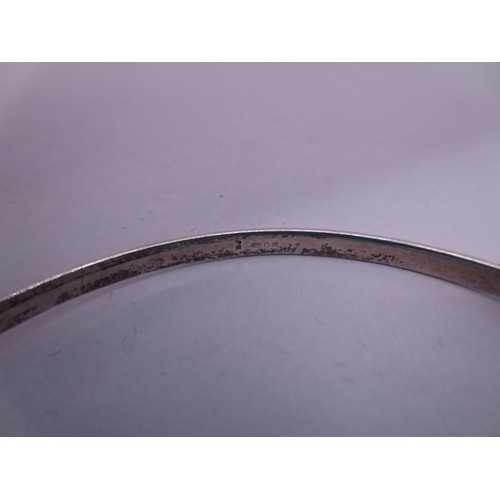 74 - A silver bangle with a looped clasp, marks for  London, 2006, indistinct maker's stamp