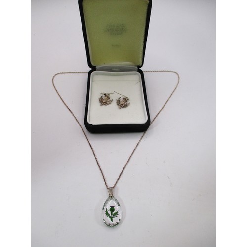 A sterling silver chain with glass pendant featuring a painted thistle ...