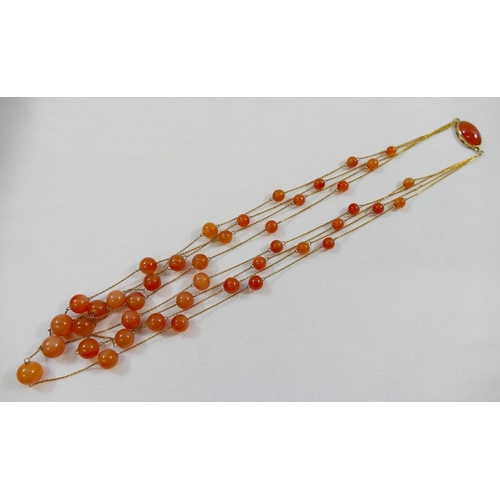 196 - A carnelian and yellow metal four strand necklace, each strand comprised of a fine yellow metal chai... 