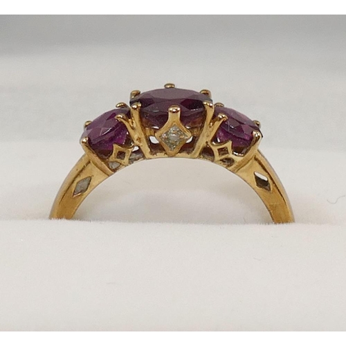 231 - A 9 carat gold almandine garnet three stone ring, the round mixed cut garnets in claw settings, the ... 