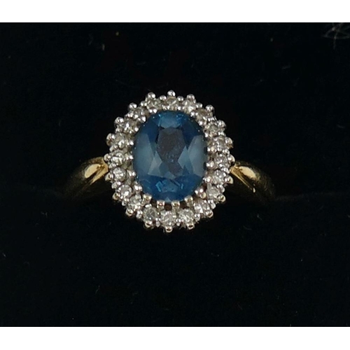 235 - An 18 carat gold topaz and diamond oval cluster ring, London 1989, the oval mixed cut topaz within 2... 