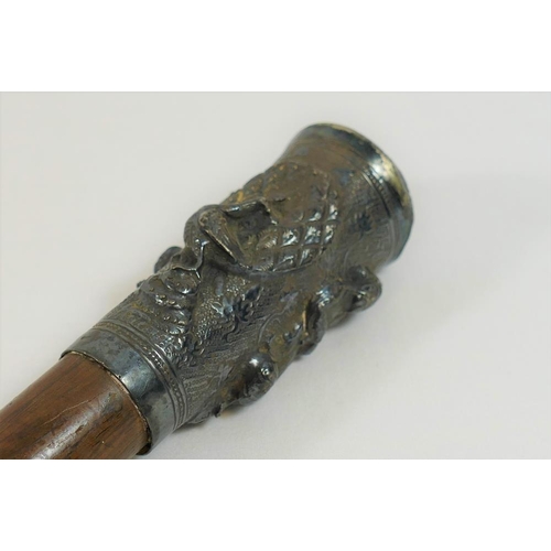 182 - A malacca cane, the embossed silver coloured metal top decorated in relied with two figures and a pe... 