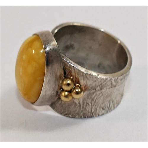 162 - A modern silver and amber dress ring, London 2010, maker's mark IMV, the oval amber cabochon in rub ... 