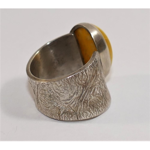 162 - A modern silver and amber dress ring, London 2010, maker's mark IMV, the oval amber cabochon in rub ... 