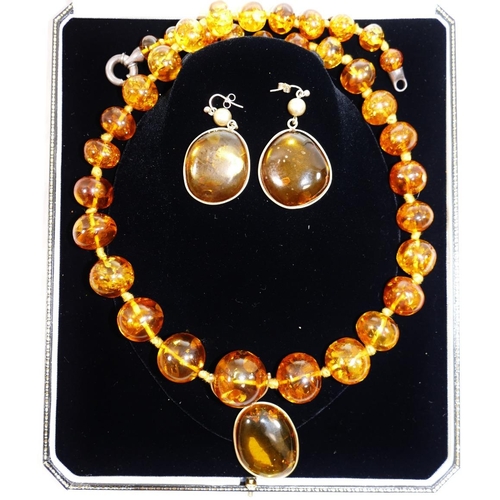 164 - A modern amber bead necklace, with silver coloured metal clasp, 65cm long, with later pendant drop a... 