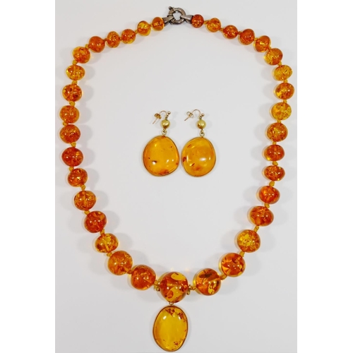 164 - A modern amber bead necklace, with silver coloured metal clasp, 65cm long, with later pendant drop a... 