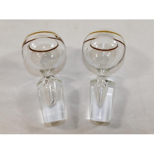 29 - A pair of Murano clear glass decanters with gilt rims, raised on pedestal bases with hollow gilt ban... 