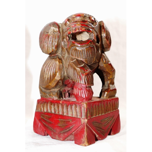 33 - A small pair of Chinese carved wooden temple dogs of foo, painted in red and gilt, on square bases, ... 