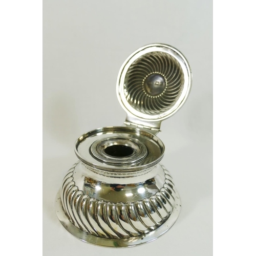 49 - A late Victorian silver circular ink well, with half reeded body and hinged lid, on plain spreading ... 