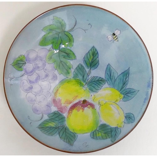 43 - A 20th century Chelsea Pottery dish, hand decorated in enamels on a blue ground with a bee, apples, ... 