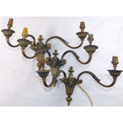 80 - Three two-light brass wall lights, of neoclassical design cast with ram's head and acanthus leaf dec... 