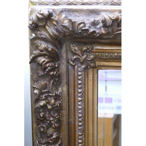 132 - A large rectangular gilt framed wall mirror with heavily moulded frame and bevelled glass plate, the... 