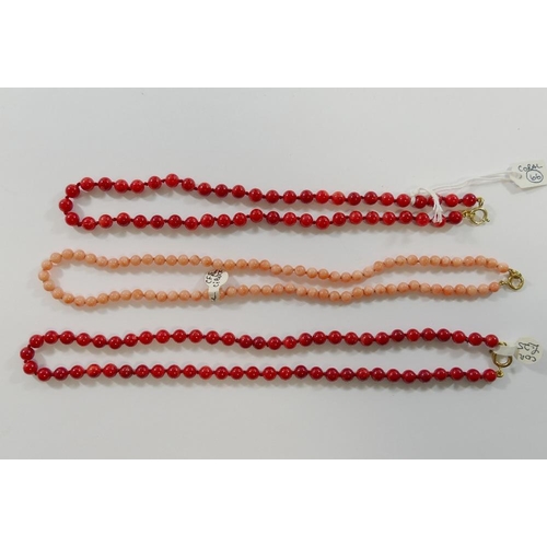 227 - Two strings of individually knotted red coral bead necklaces, with a pair of matching drop earrings ... 