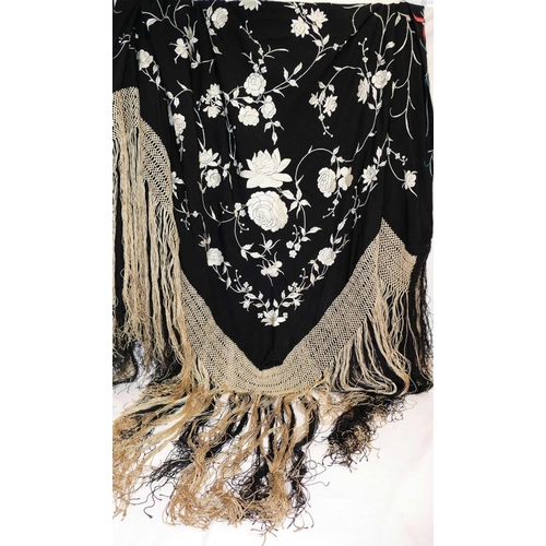 375 - A large Chinese black embroidered shawl, decorated with polychrome flowers with cream and black tass... 