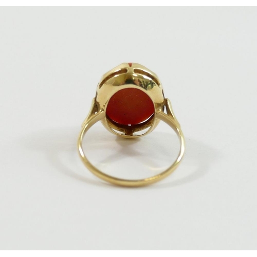 17 - An oval coral cabochon in unmarked yellow metal ring mount, finger size K, 3.7g gross