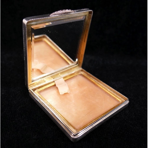 118A - A square silver powder compact, with engine turned decoration, rose coloured thumb piece, and gilt i... 