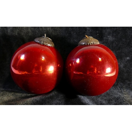 139 - A pair of glass witches balls, with red interiors, fitted with moulded metal mounts, 10cm diameter