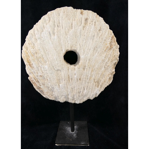 167 - A large coral circular carved disc with central hole, (similar to that of a rai stone), raised on bl... 