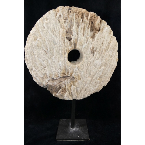 167 - A large coral circular carved disc with central hole, (similar to that of a rai stone), raised on bl... 