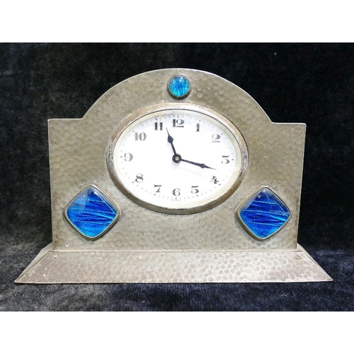 202 - An Arts and Crafts pewter mantle timepiece, set with simulated butterfly wing panels, with white ova... 