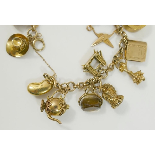 24A - A fancy link yellow metal chain hung with nineteen 9ct gold charms and three additional 9ct gold cha... 