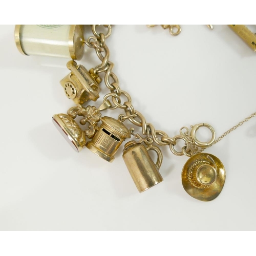 24A - A fancy link yellow metal chain hung with nineteen 9ct gold charms and three additional 9ct gold cha... 