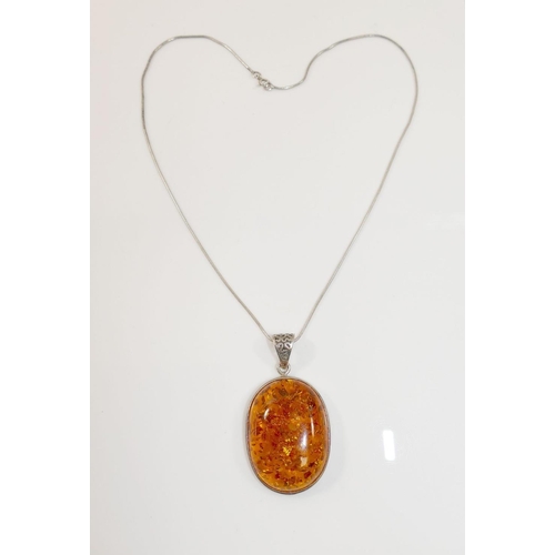 32A - A large clarified amber oval pendant on snake link chain, stamped '925', an amber bracelet with simi... 