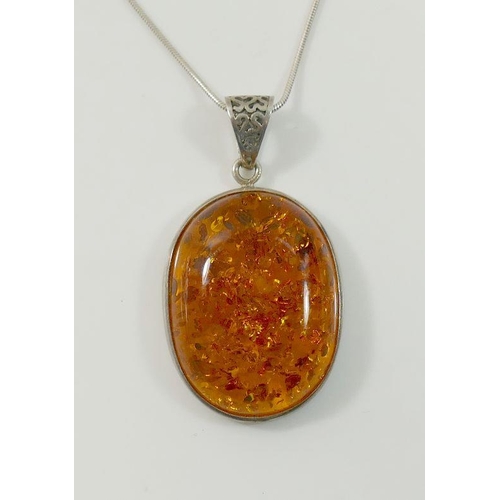 32A - A large clarified amber oval pendant on snake link chain, stamped '925', an amber bracelet with simi... 